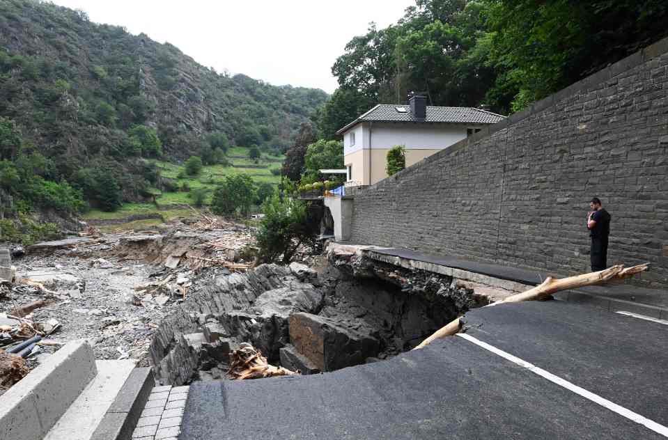 A policeman looks at a piece of road that has sunken in the city of Altenahr, Germany