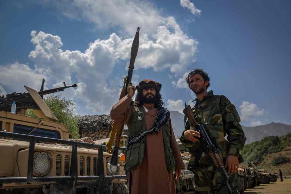 Troops stand with assault rifles and RPGs