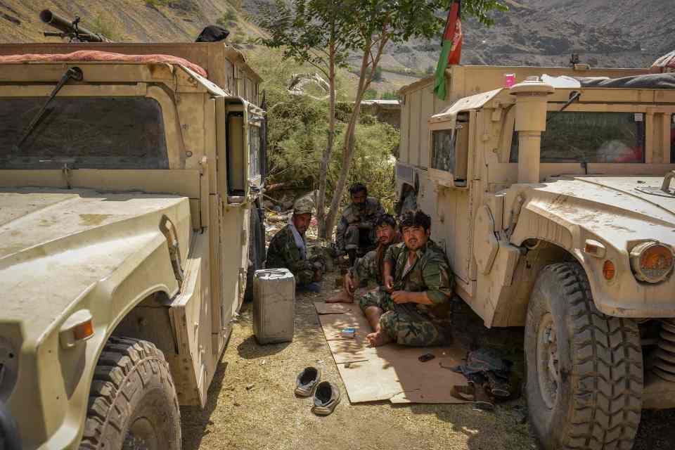 Troops rest by their humvees in the sun