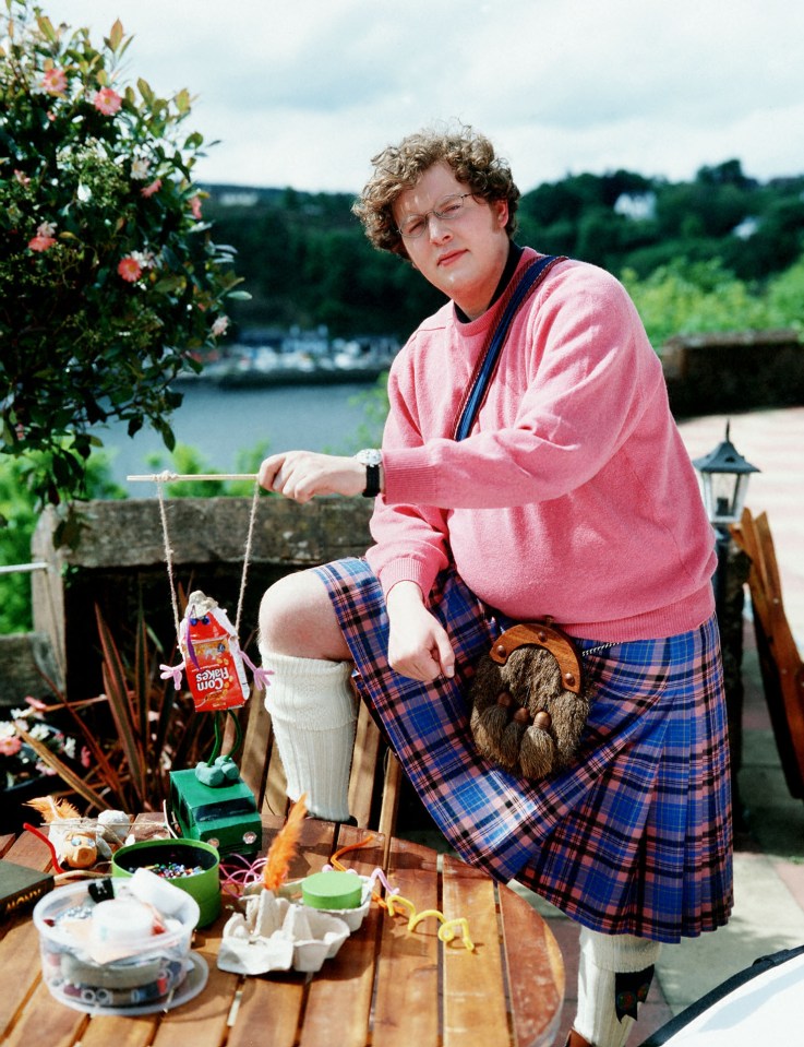 a man in a kilt sits at a table with a bag of saltines on it