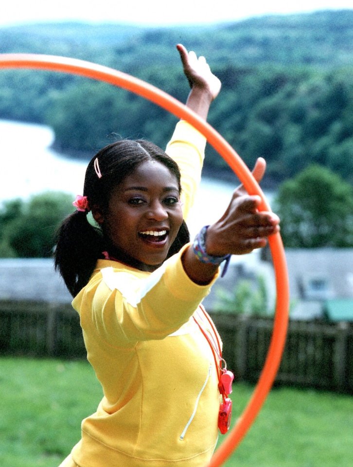 a girl in a yellow shirt is playing with an orange hula hoop