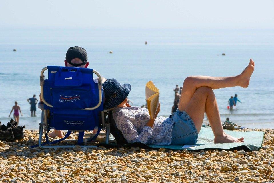 A sunbather enjoys a good book on the pebbles in Bournemouth