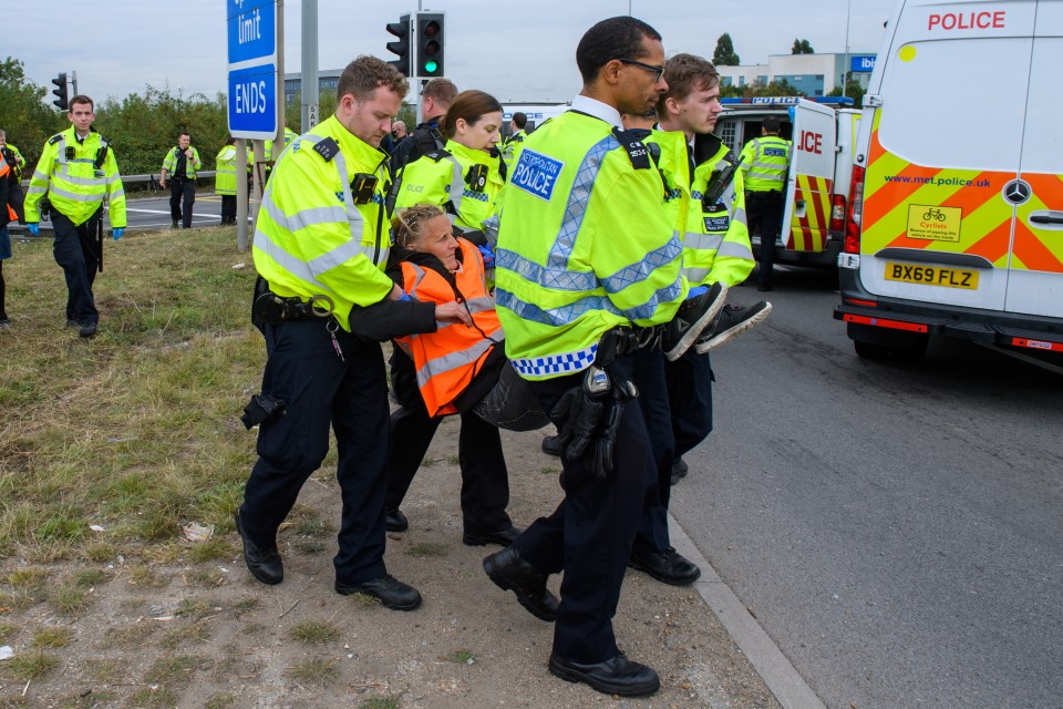 Police officers remove the last protester at the clockwise slip road at Junction 14