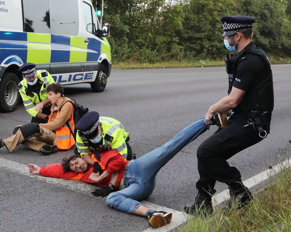 Police attempt to haul a resistant protester off the tarmac