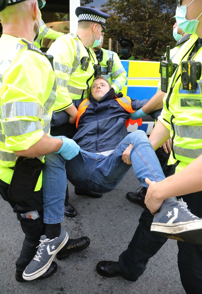Three police officers carry one protester off the motorway