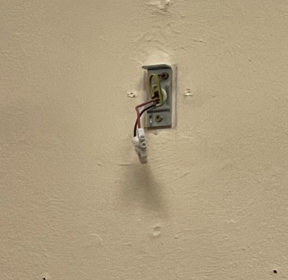 Cabling is pictured exposed and hanging from a wall