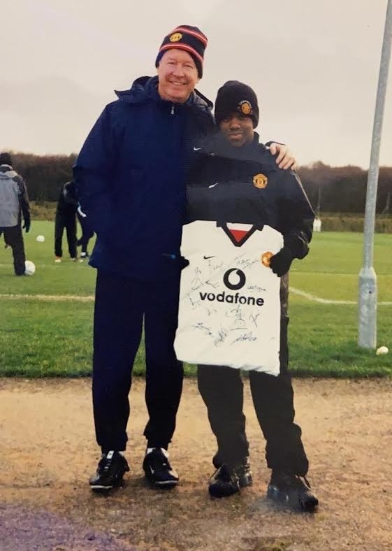 Photo of Sir Alex Ferguson with a young boy holding a signed Manchester United jersey.