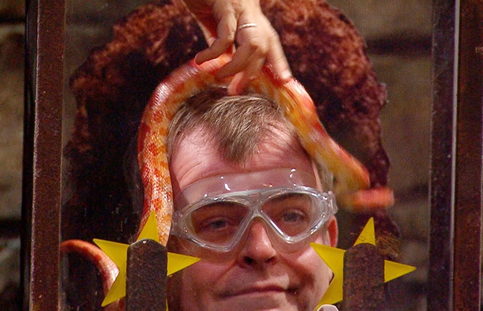 Simon Gregson grimaces while a snake wraps itself around his haed