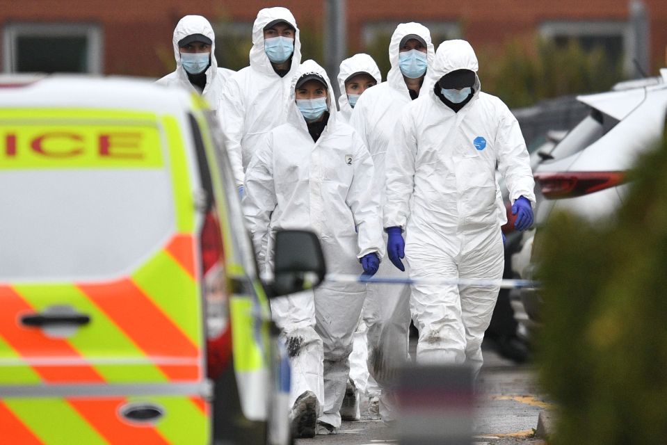 Forensics officers walk near the scene of the car blast outside the Women's Hospital in Liverpool