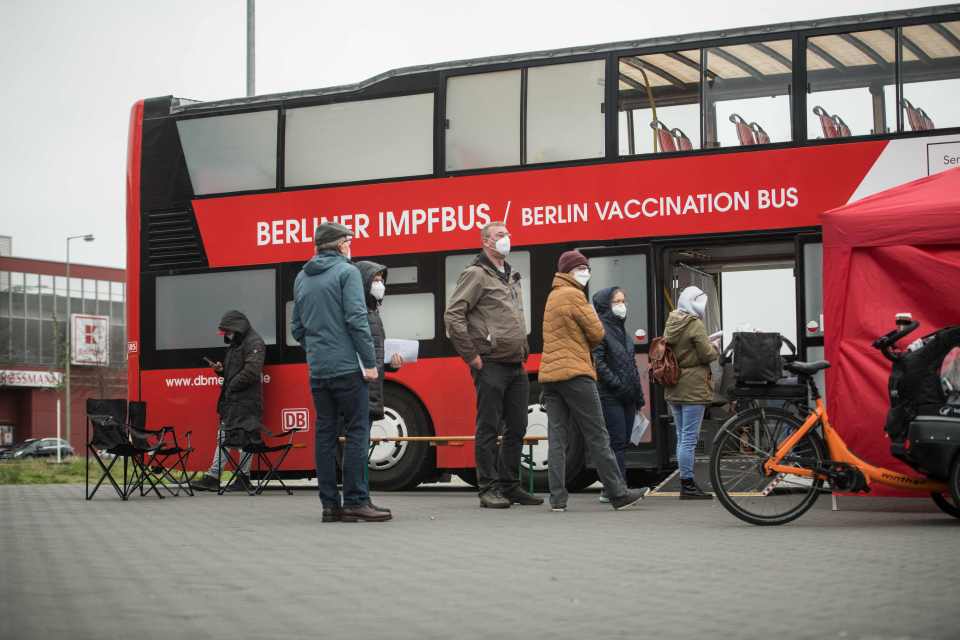 People stand in line in front of a vaccination bus to get vaccinated in Germany