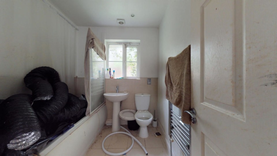 Even the bathroom is filled with black ventilation pipes and the toilet seat is missing