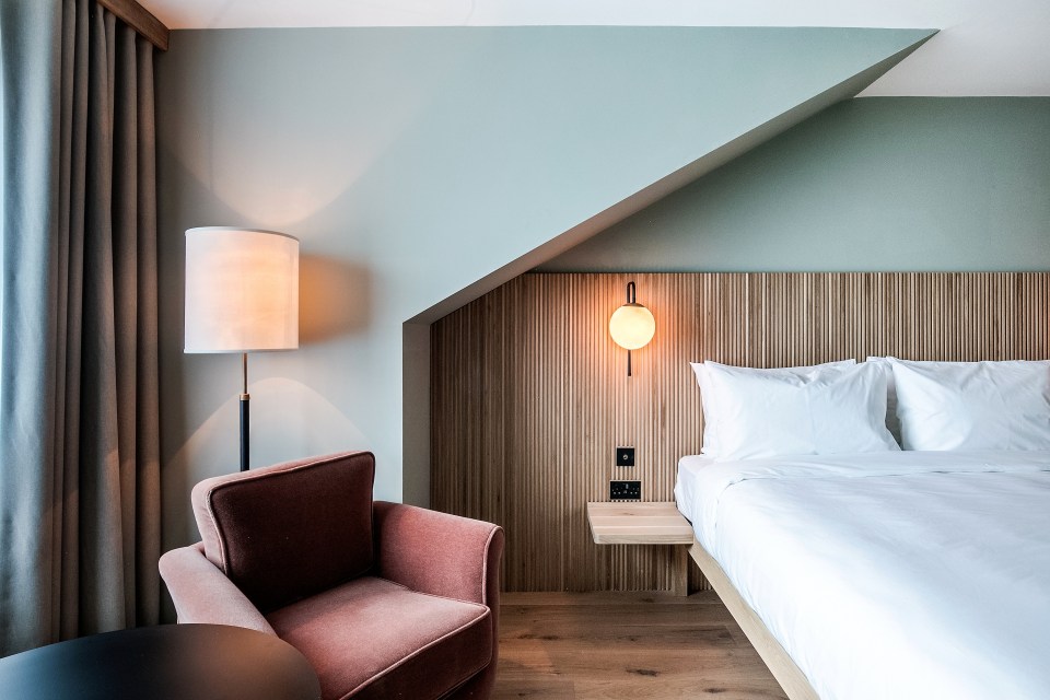 Hotel room with a bed, armchair, and floor lamp.