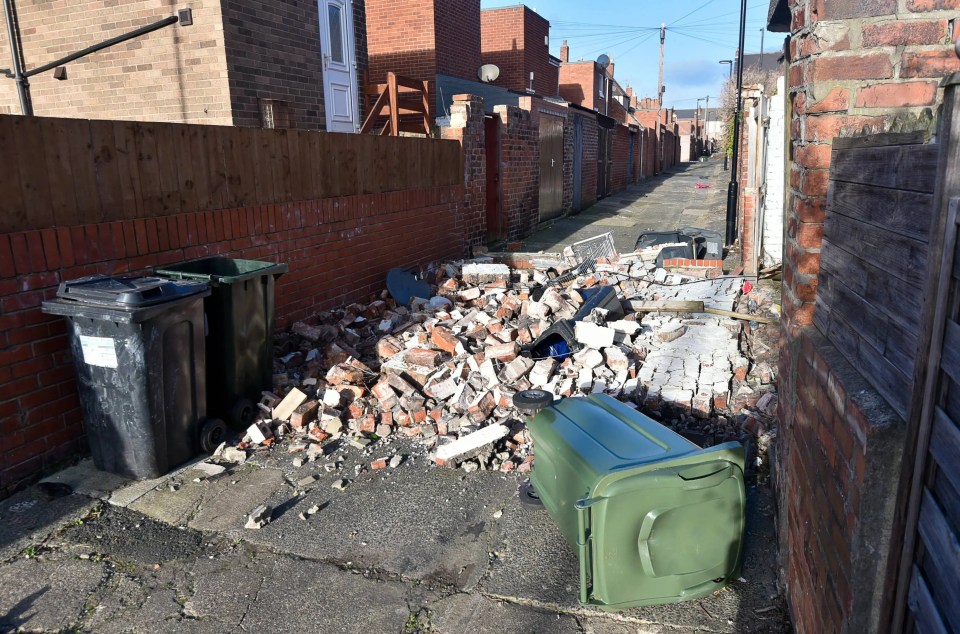 Wheelie bins lie on the ground and bricks litter the pathway after a wall collapsed in a back lane in North Shields