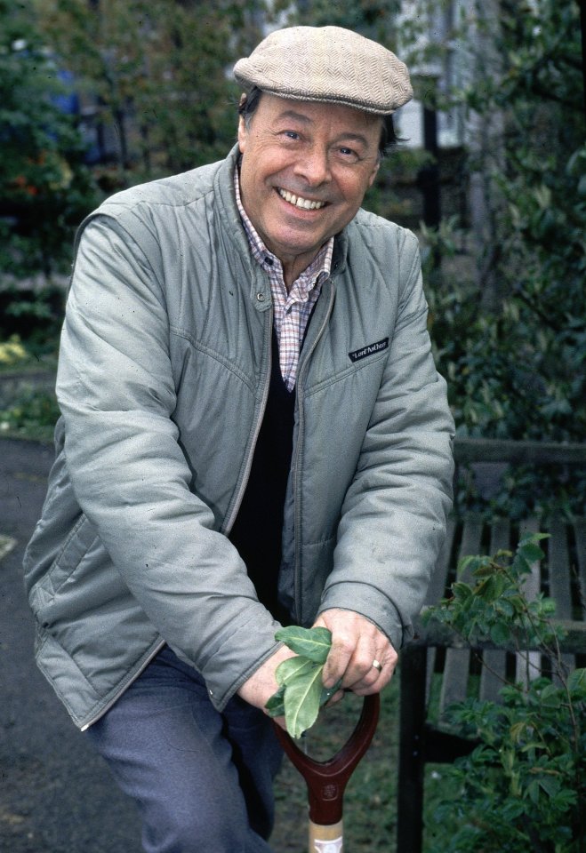 Bill Treacher as Arthur Fowler holding a gardening tool.