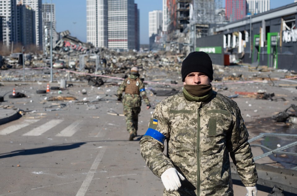 Ukrainian servicemen are seen at the site of a rocket strike at a shopping centre in Kyiv