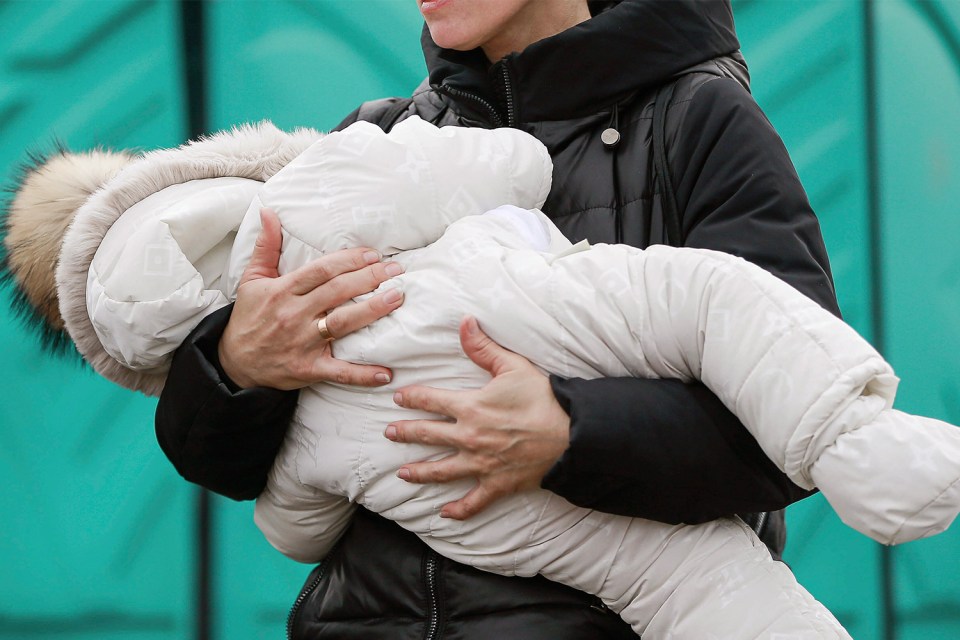 A Ukrainian mother holding her baby as she crosses into Poland