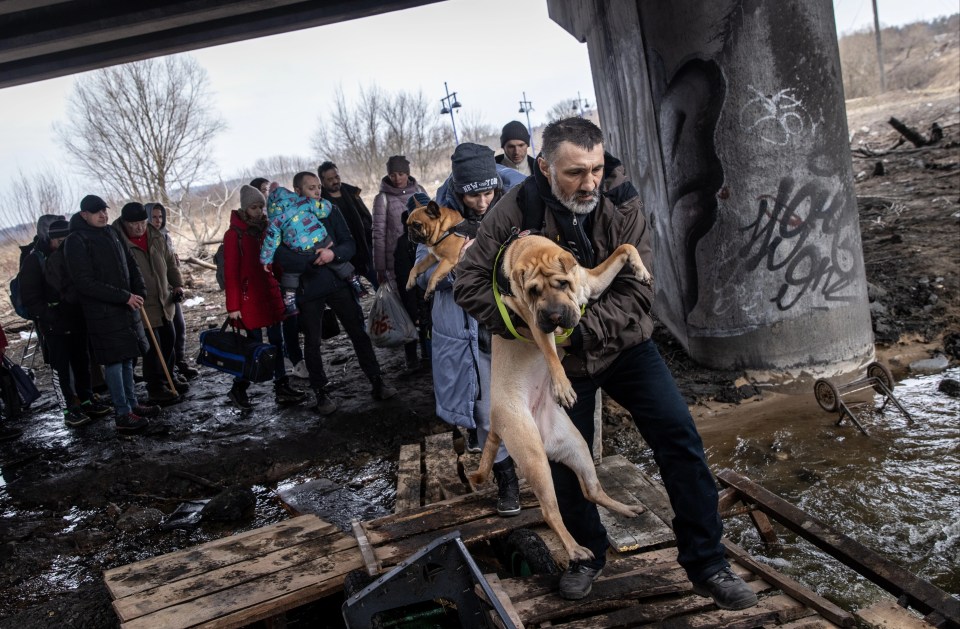 Families carry children and pets in their arms as they try to leave besieged Irpin