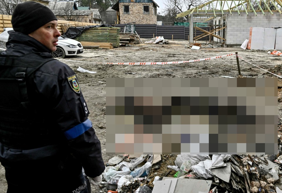 A policeman stands guard next to six partially burnt bodies in Bucha