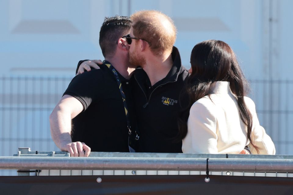 Prince Harry embraces Paralympian Dave Henderson with a hug and kiss on the cheek
