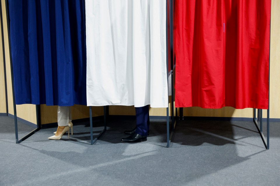 French President Emmanuel Macron and his wife Brigitte Macron stand in the voting booths
