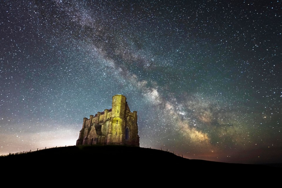 The Milky Way glows brightly in the clear night sky above St Catherine's Chapel at Abbotsbury in Dorset on the first day of meteorological summer