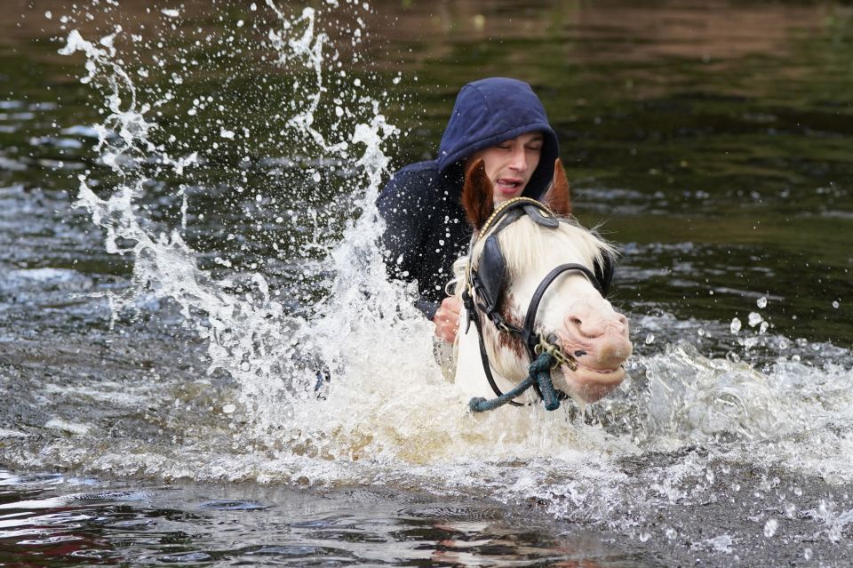 A lad rode his horse up to its neck in the river