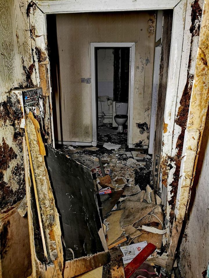 Interior of a fire-damaged apartment, showing debris and a damaged bathroom.