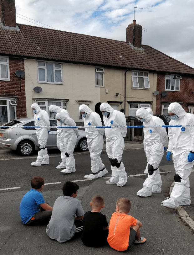Children watch on as forensic officers hunt for clues