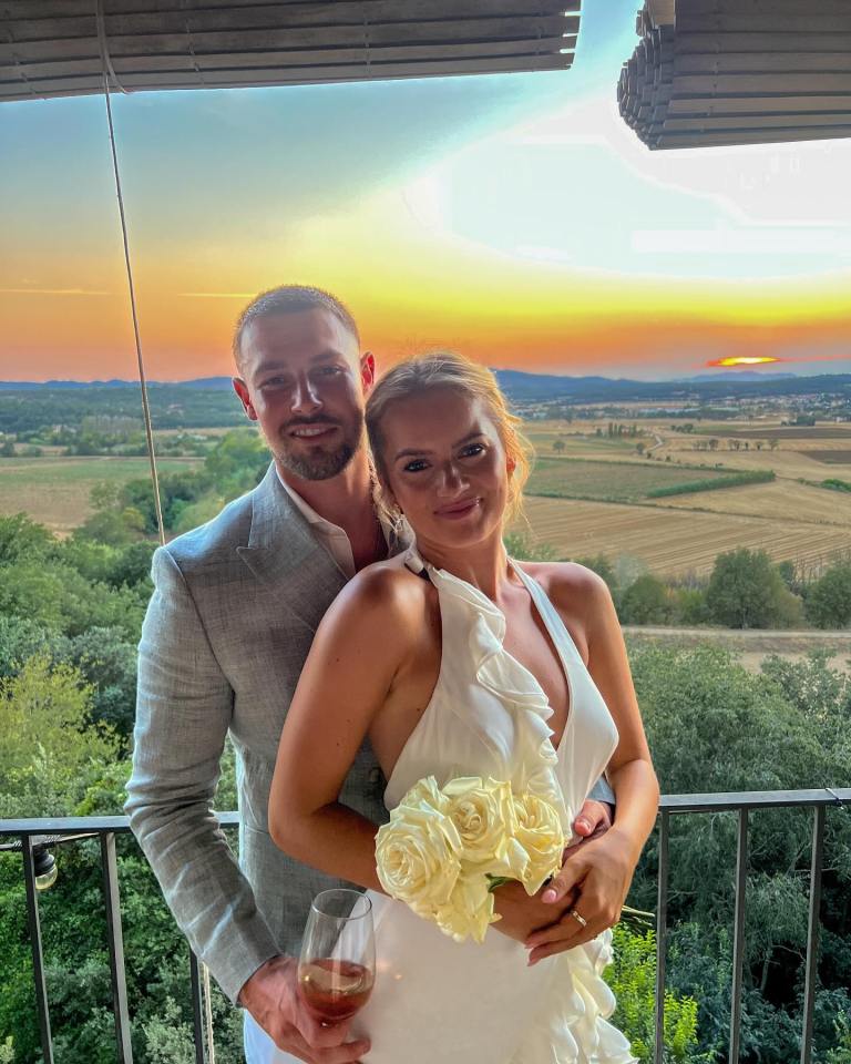 a bride and groom pose for a picture with a sunset in the background