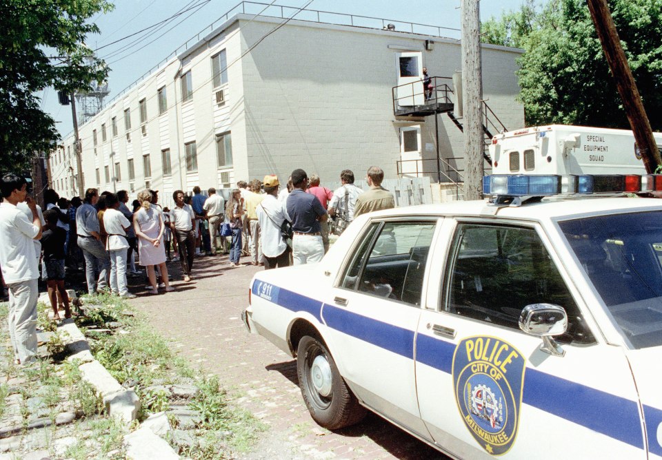 Neighbours gather near Dahmer's apartment building on July 24, 1991, as police  investigate their discovery of body parts