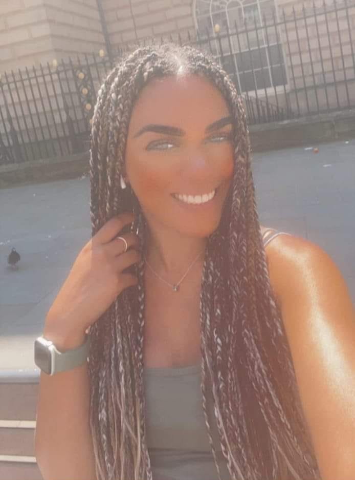 a woman with braids is smiling and wearing an apple watch