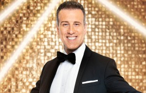 a man in a tuxedo is dancing in front of a gold background