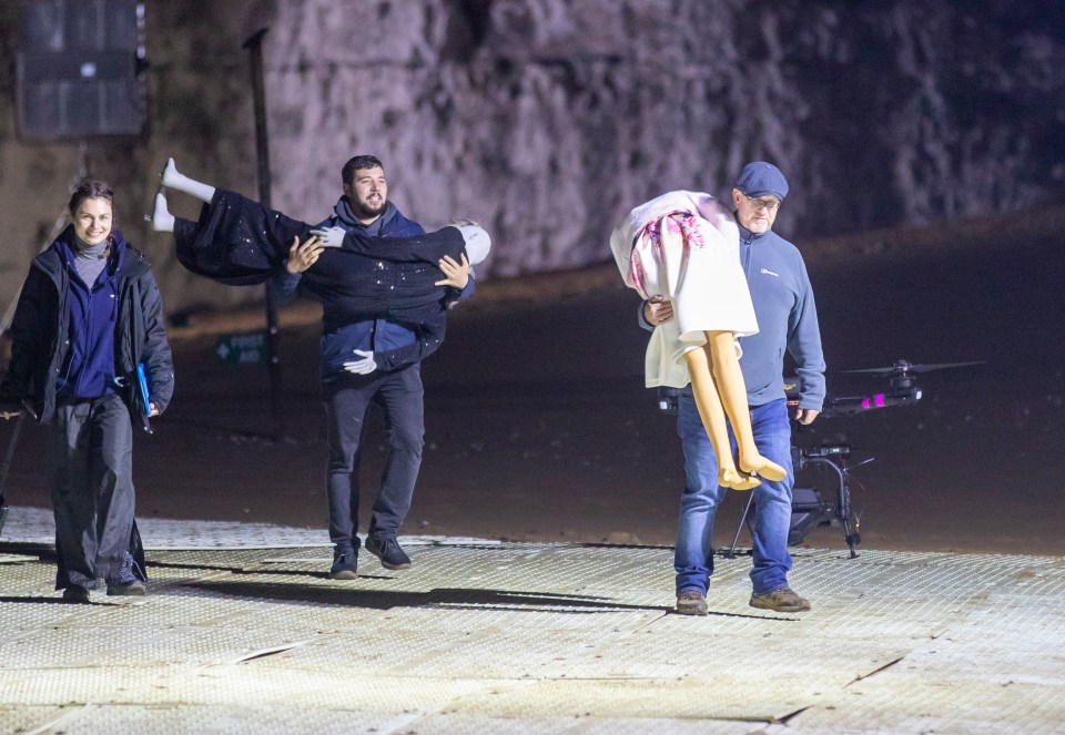 Two crash dummies dressed like Linda and Janine are carried onto set