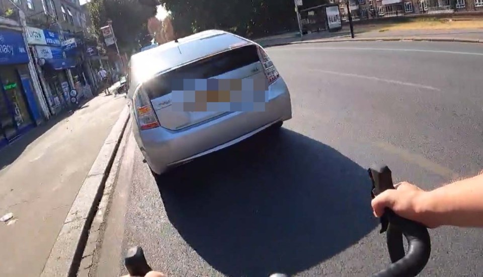The Toyota Prius stops in front of the cyclist