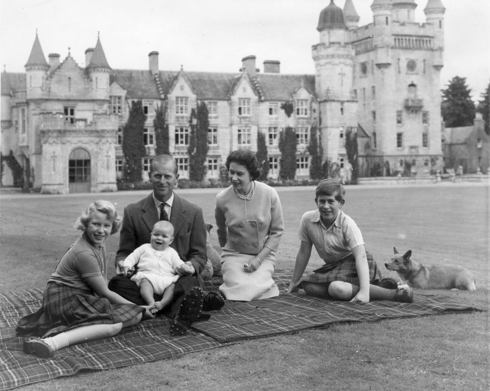 Queen Elizabeth II and Prince Philip with Prince Andrew, Princess Anne and Charles sitting on a picnic rug outside Balmoral Castle