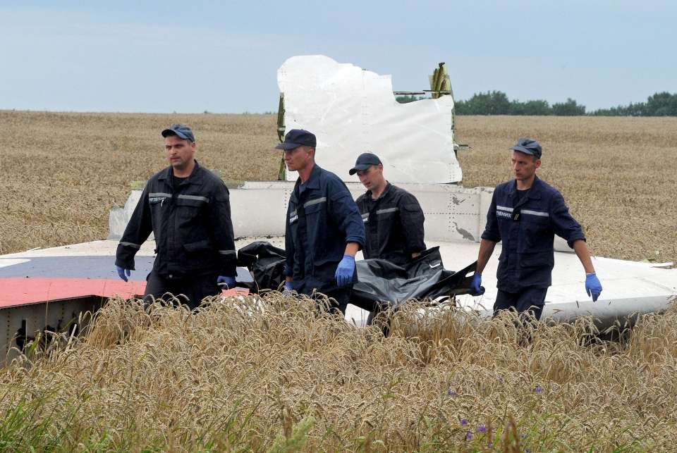 Ukrainian rescue workers walk past a piece of wreckage of the plane