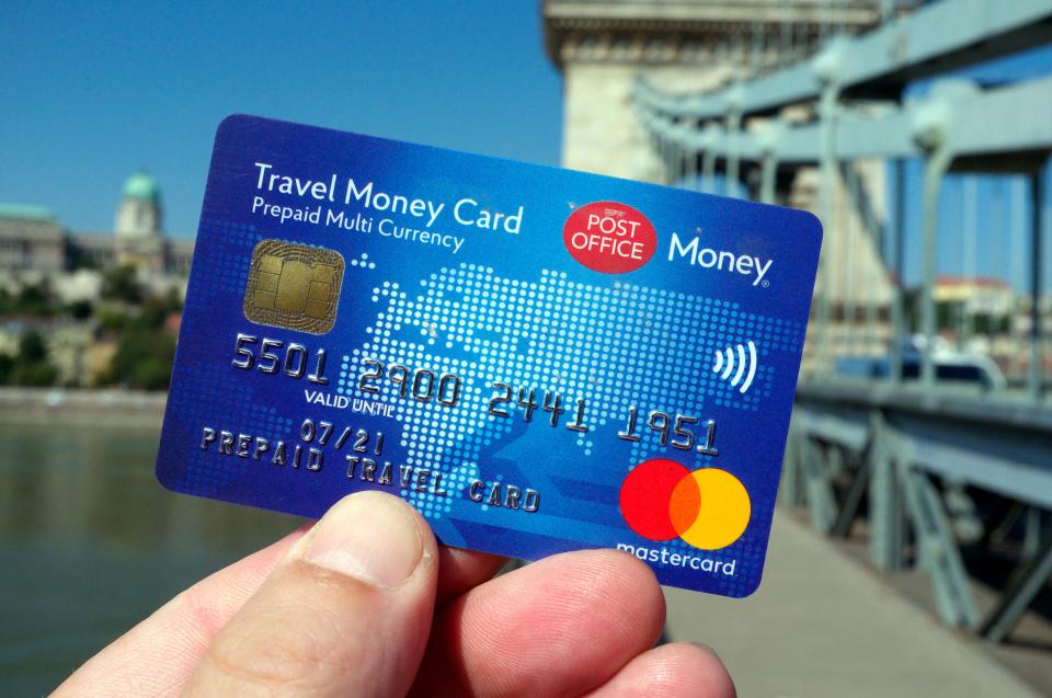 a person is holding a travel money card in their hand