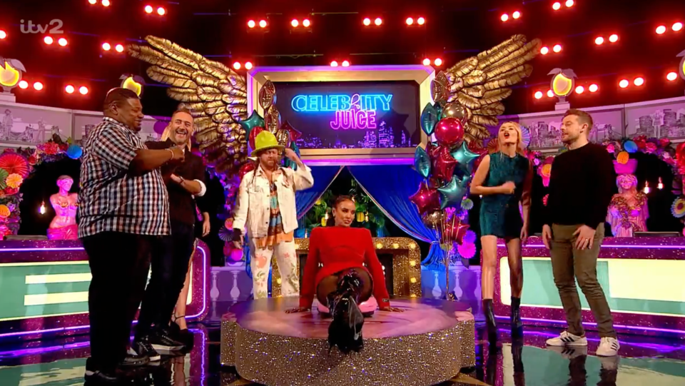 Maya jiggles about as her teammates guess the answers to her clues