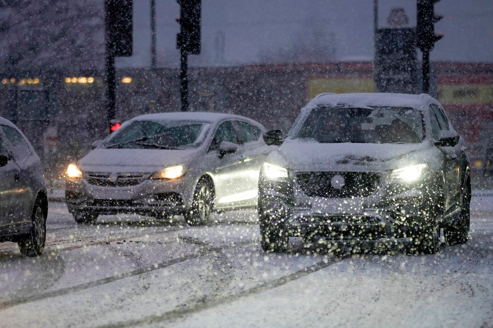 Motorists are seen driving through a snow flurry in Cheshire this morning