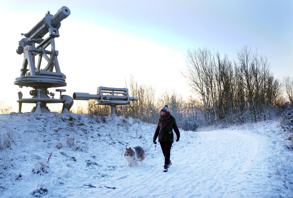A woman walks her dog through overnight snow in County Durham