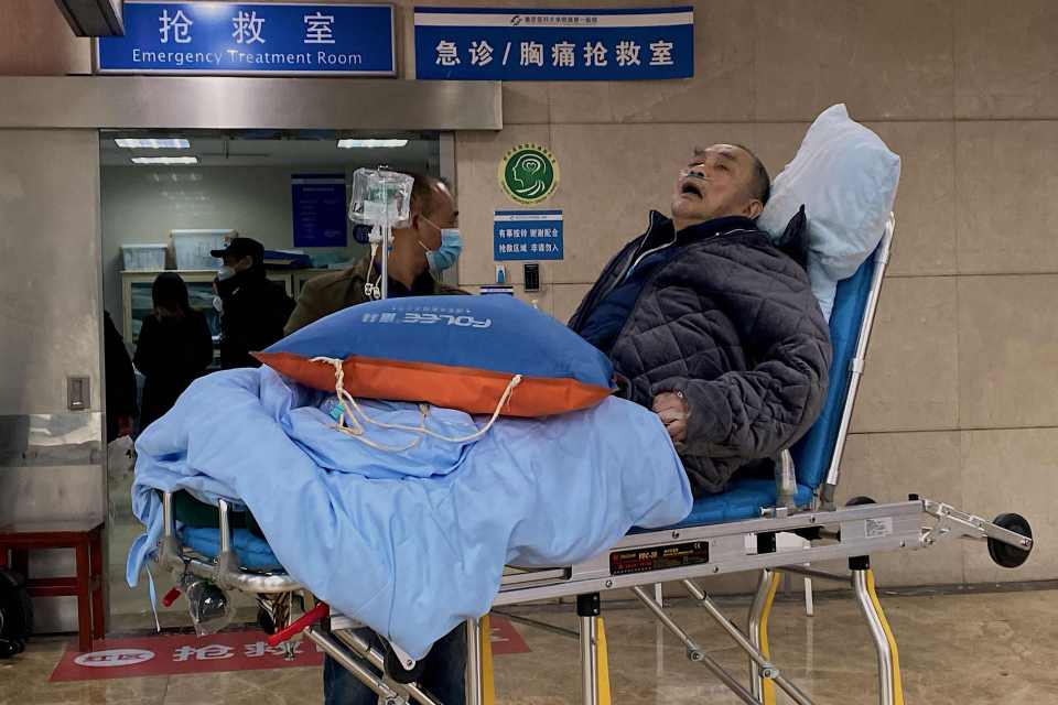 An elderly Covid patient in a coat waits for hospital treatment