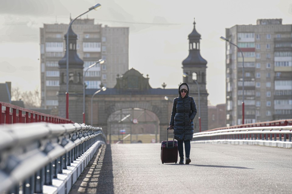 A lone Russian woman crosses over from the Russian side of the bridge