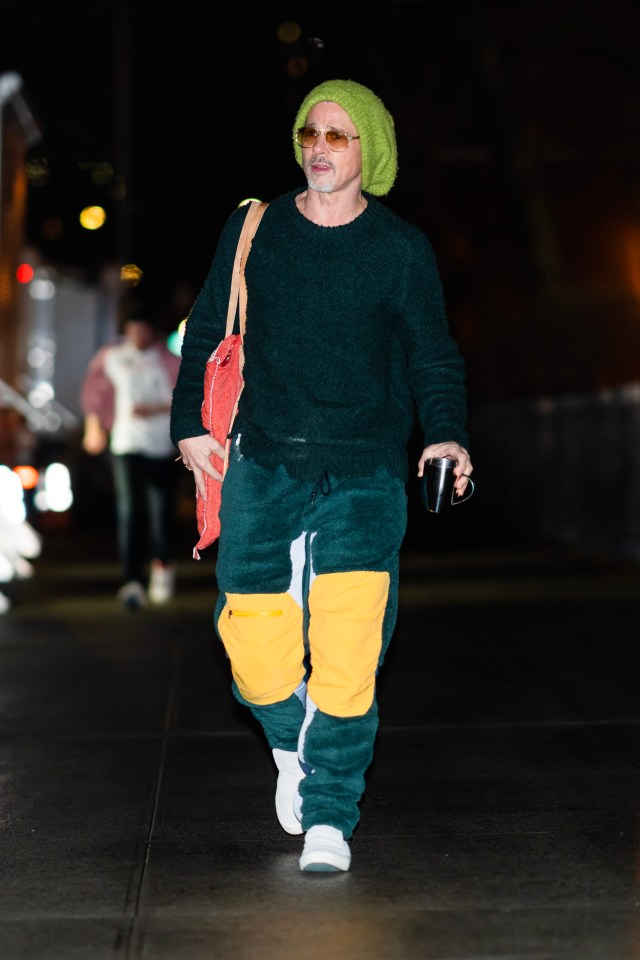 Brad Pitt in a green beanie, yellow trousers and red bag