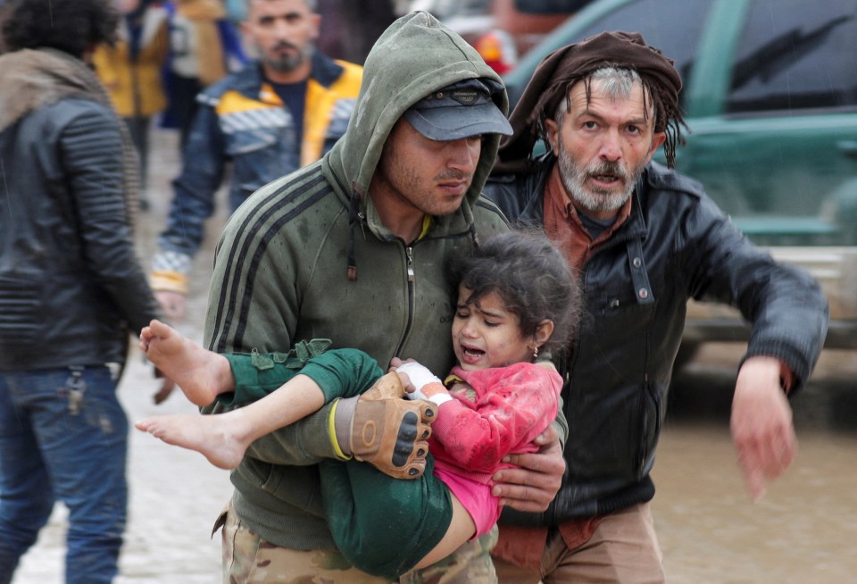 A man carries a little girl to safety after the devastating earthquake in Turkey and Syria