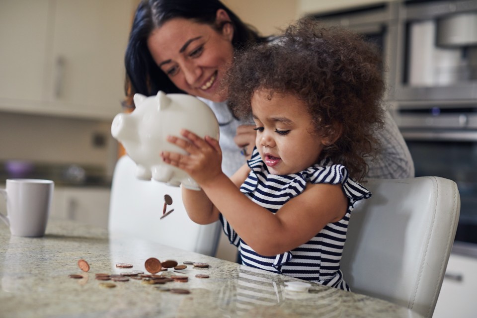 Mother and toddler girl emptying a piggy bank.
