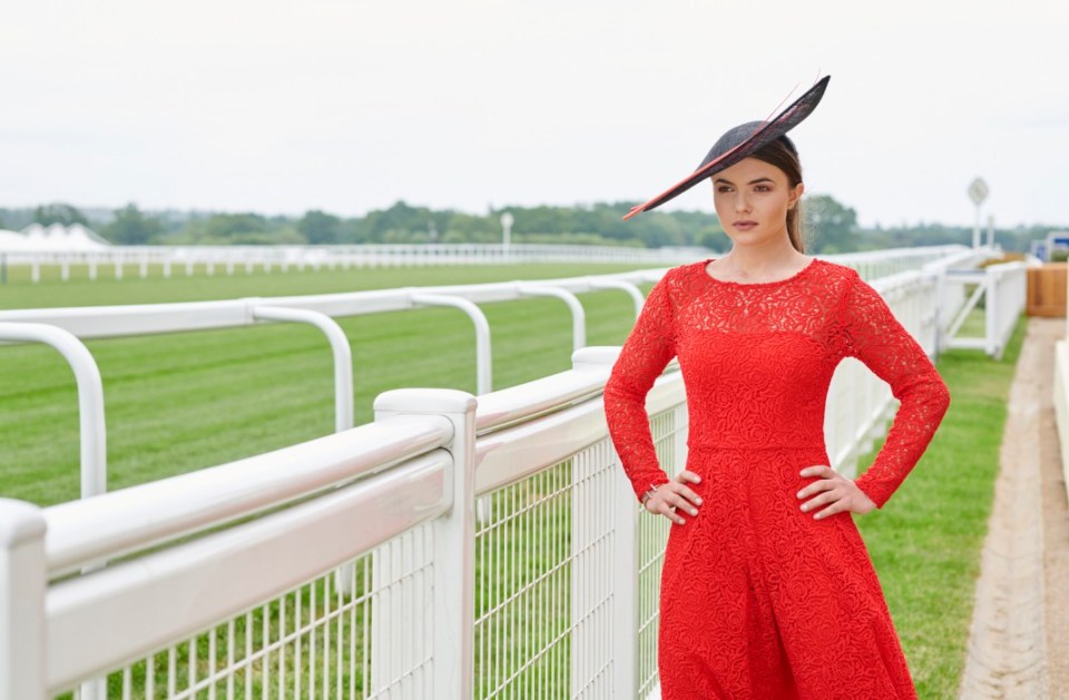 Woman in red dress and hat at a racetrack.