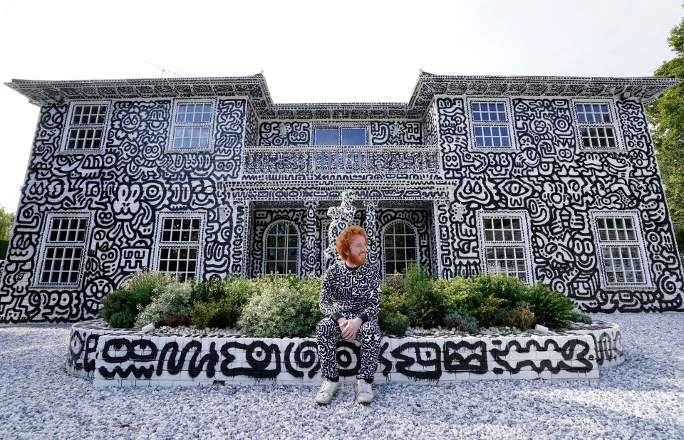 Mr. Doodle in front of his hand-drawn doodle house.