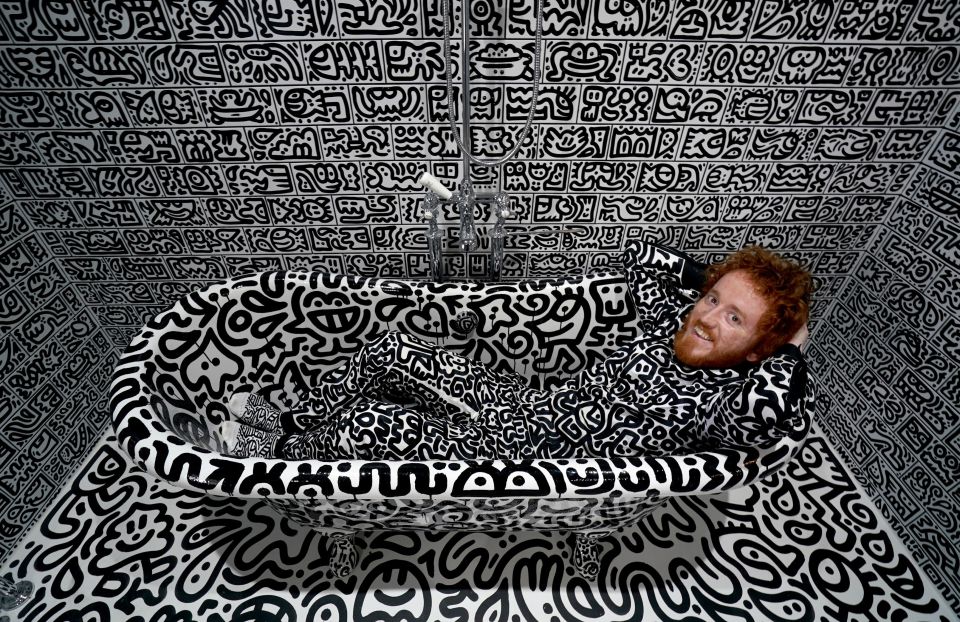 Mr. Doodle in a monochrome doodle-covered bathtub.