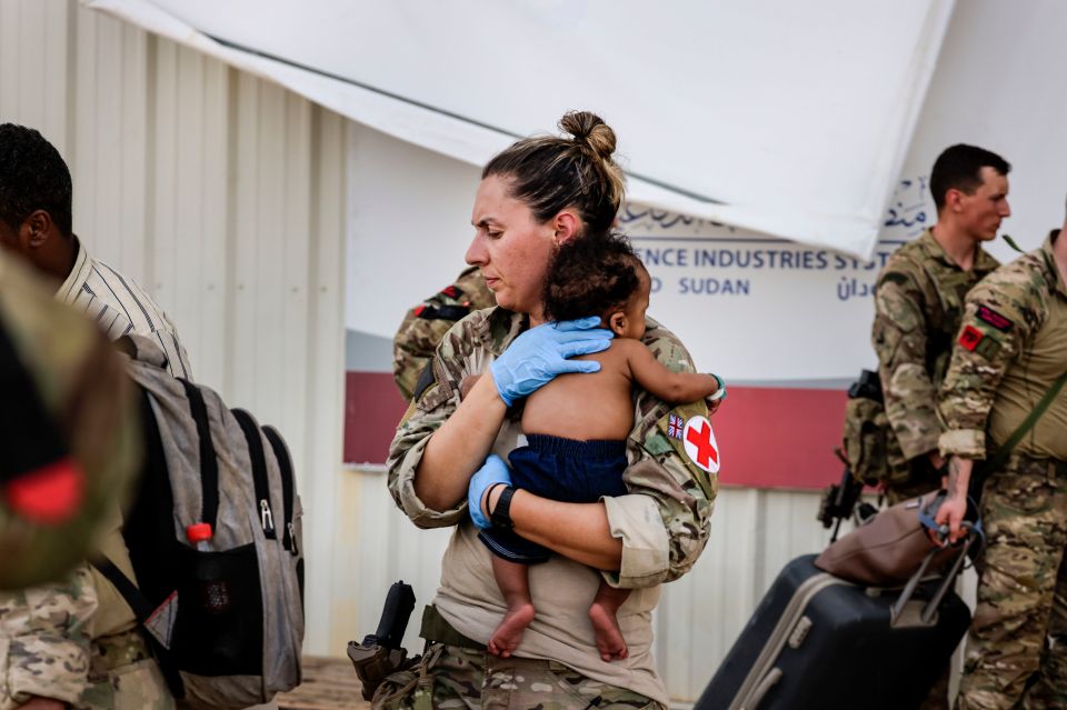 A Brit medic comforts a baby during the evacuation from Sudan