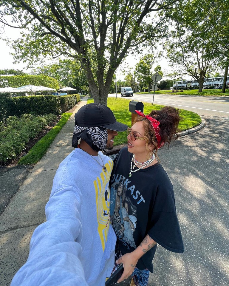a man wearing a outkast shirt stands next to a woman